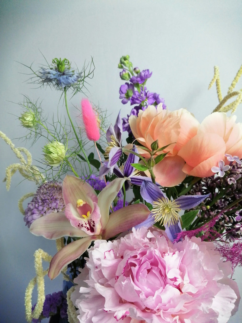 Beautiful flower arrangement, inspired by the breathtaking amalfi coast and the wonderful sunsets.  Featuring a mix of summery flowers in lovely violet, blue and coral tones like caribbean soft pink orchids, sweet scented stock, french clematis, playful bunny tails, scabiosa, Amaranthus, cerise asparagus and our star 'Peony Coral Charm' and 'Peony Angel Cheeks'.